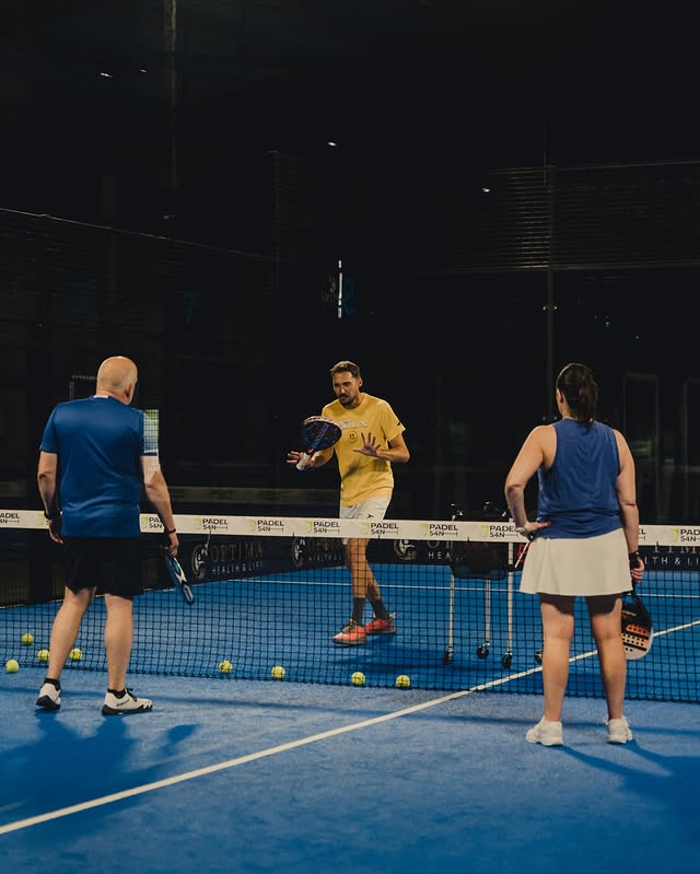 Coach working with players on an indoor padel court